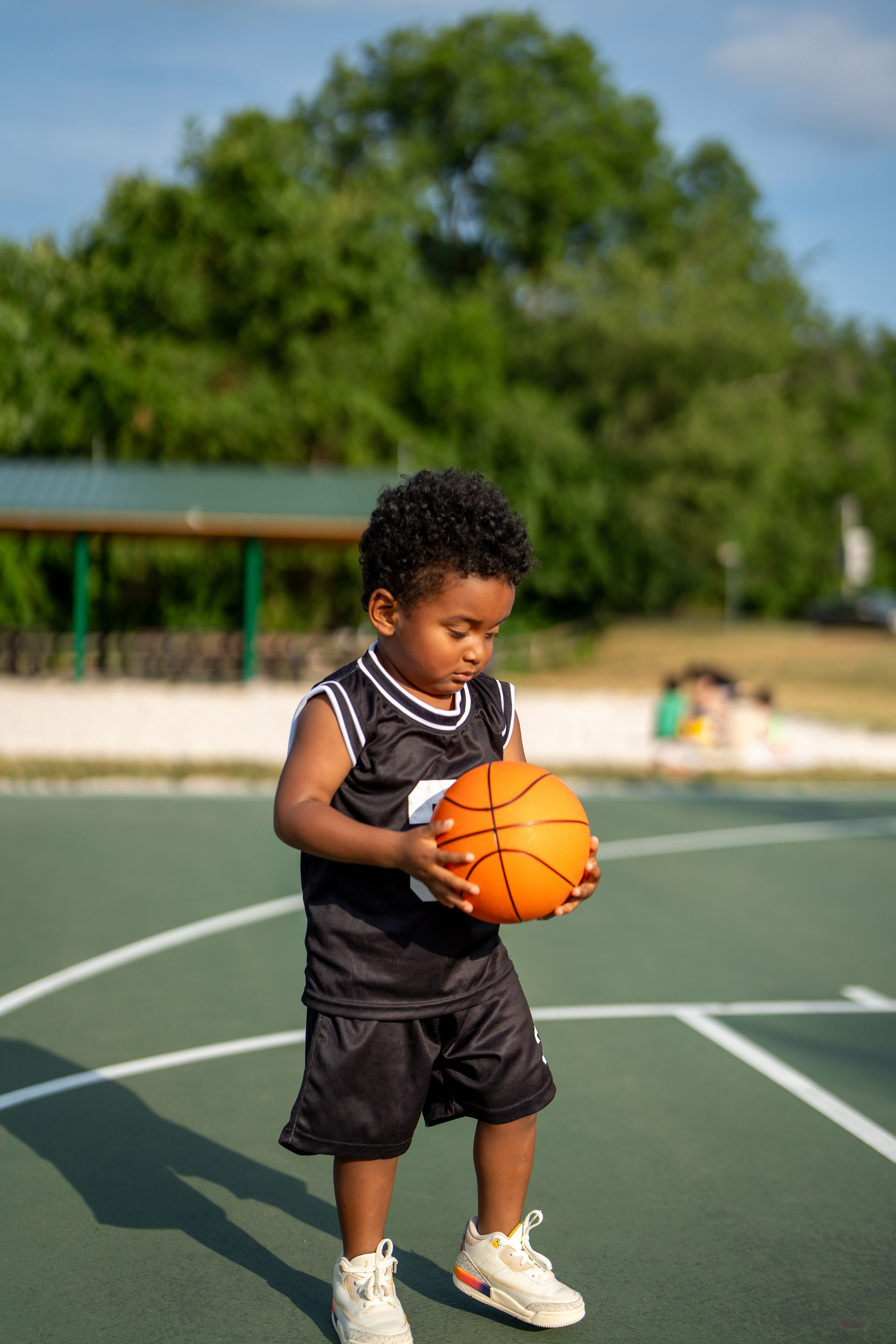 Little player holding a basketball on a green court