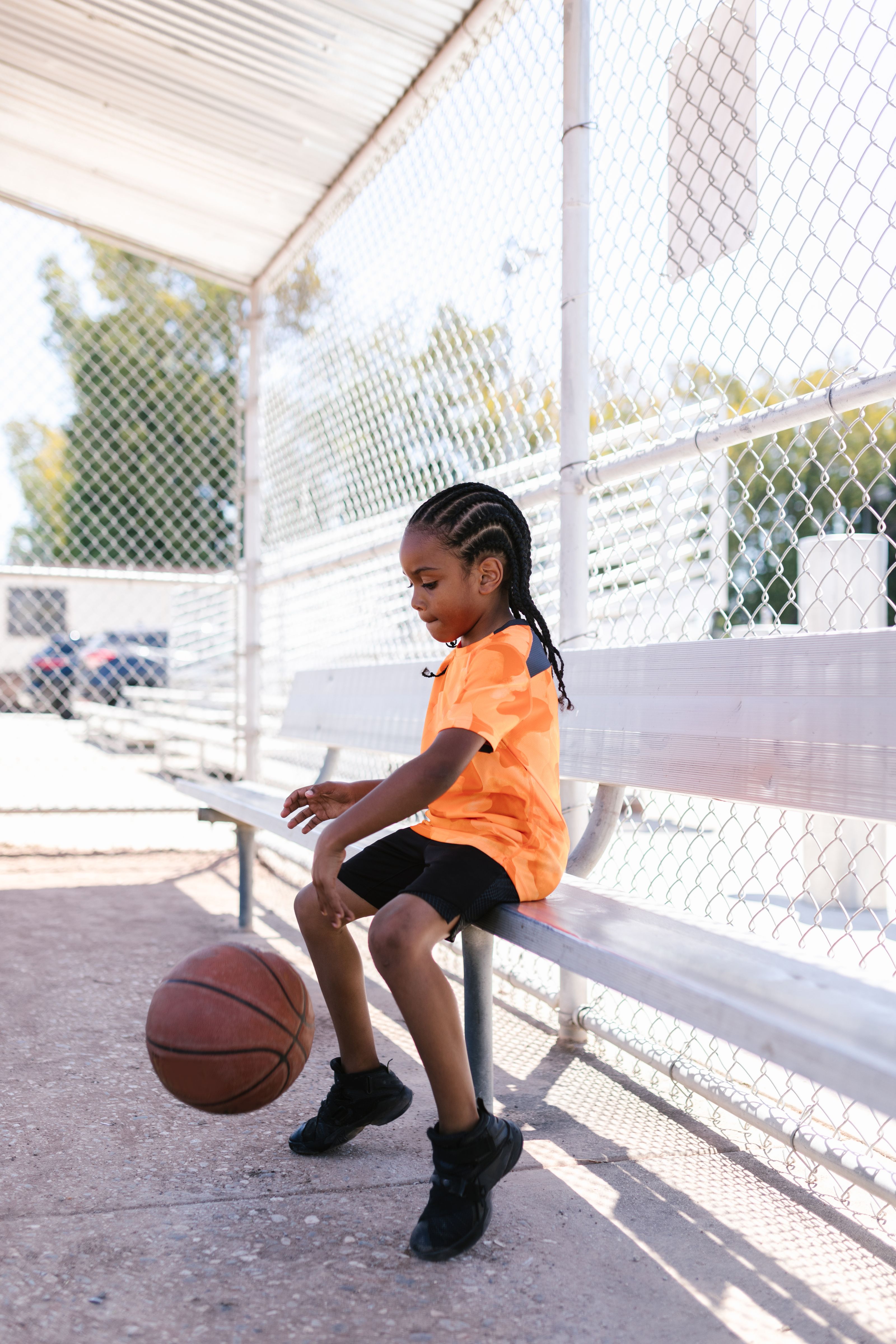 Young child bouncing a ball on the sideline