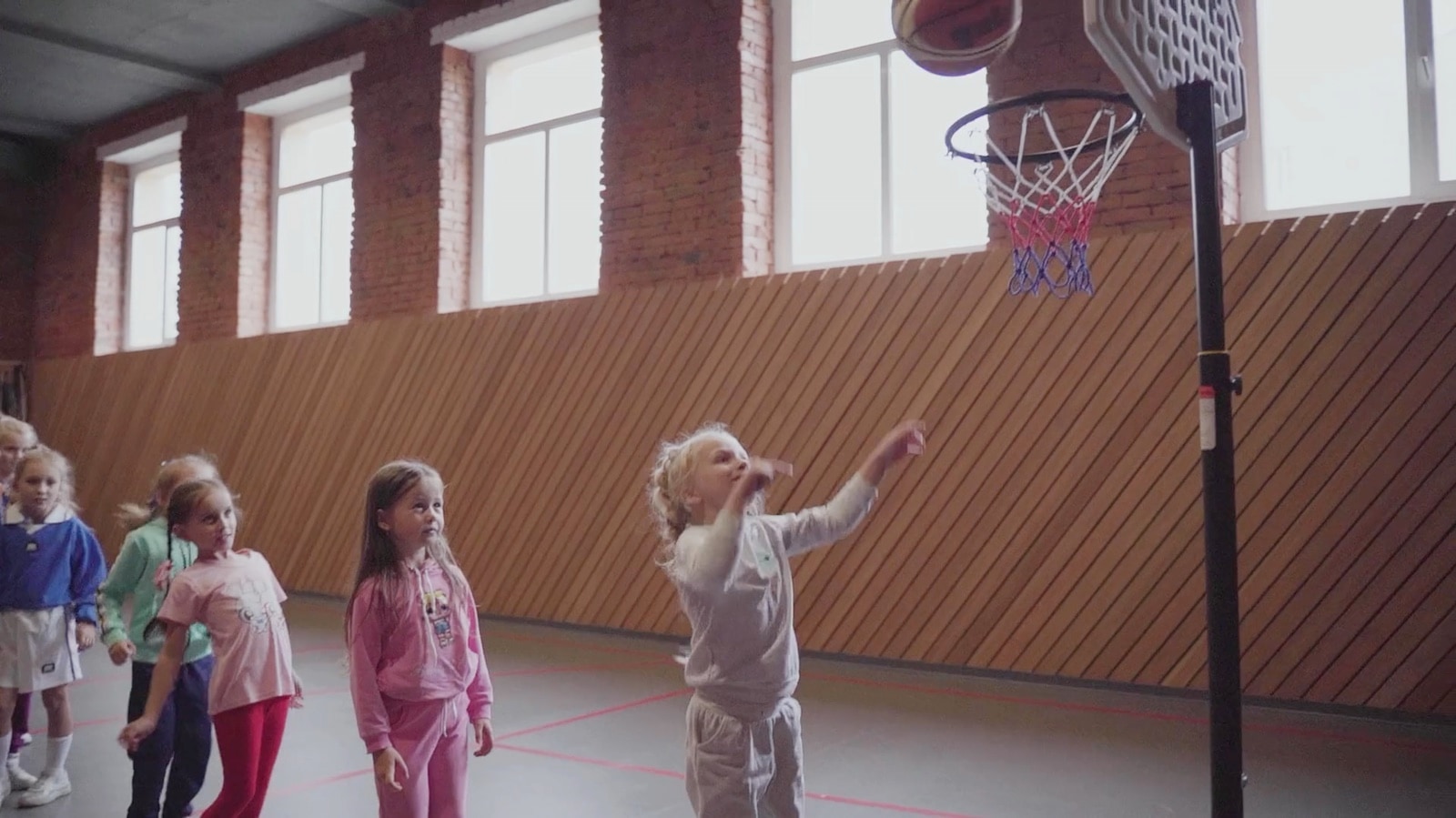 Kids ages 5–7 practicing shooting drills in a gym